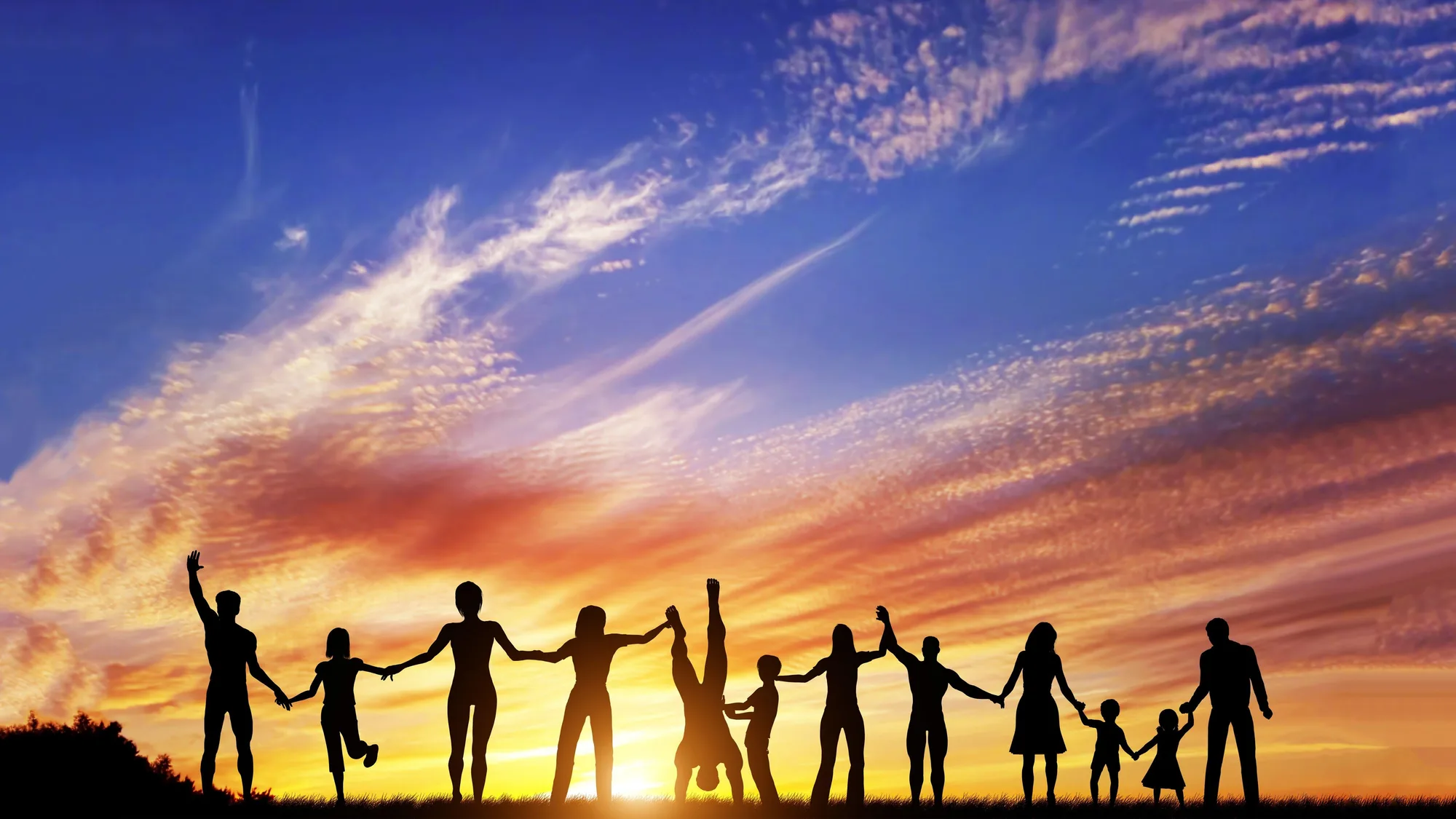 A line of people holding hands against a sunset sky